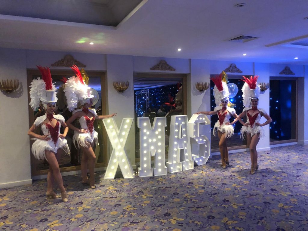 Showgirls pose with large XMAS LED sign